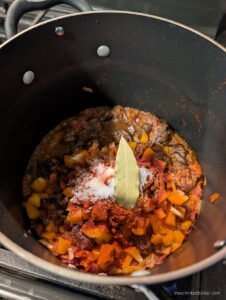 Seasoning the Goulash with paprika, salt, bay leaves, pepper