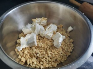 Adding the cream cheese to the crushed oreos